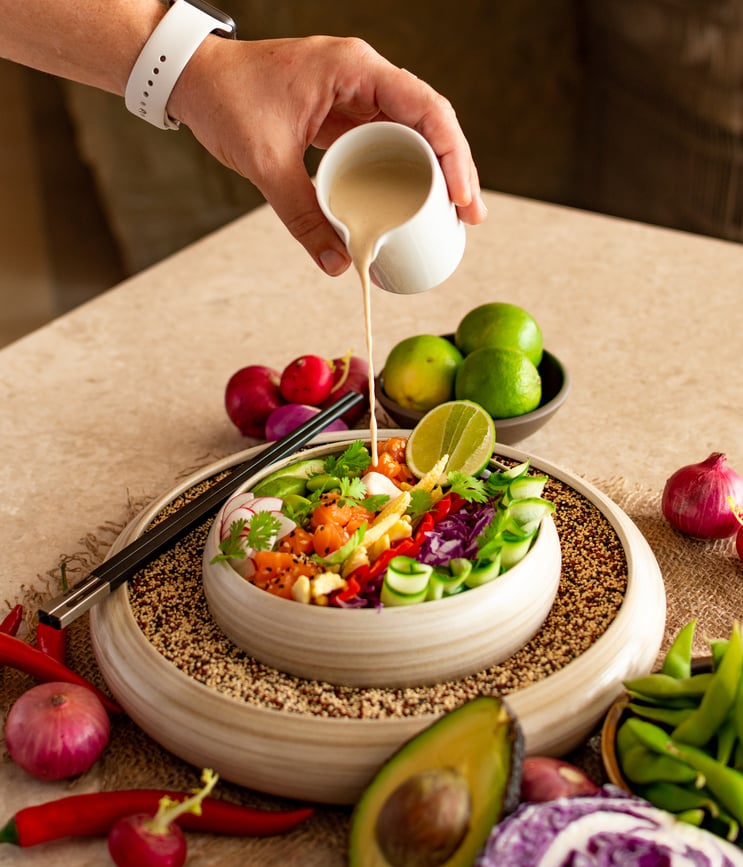 Crop person adding dressing to salad